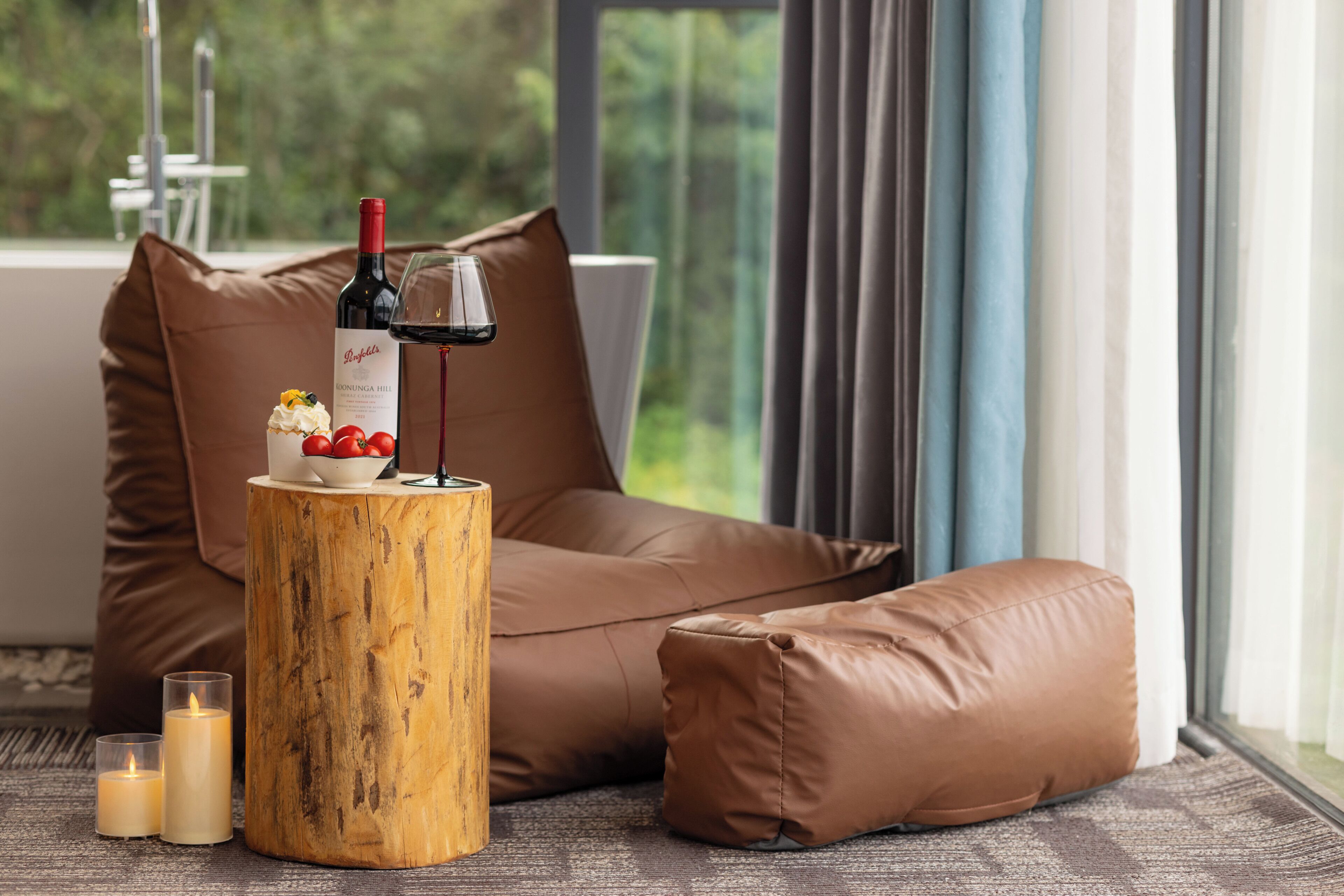 Een gezellige zithoek met een houten krukje, een fles wijn en een glas rode wijn op een tafel.
