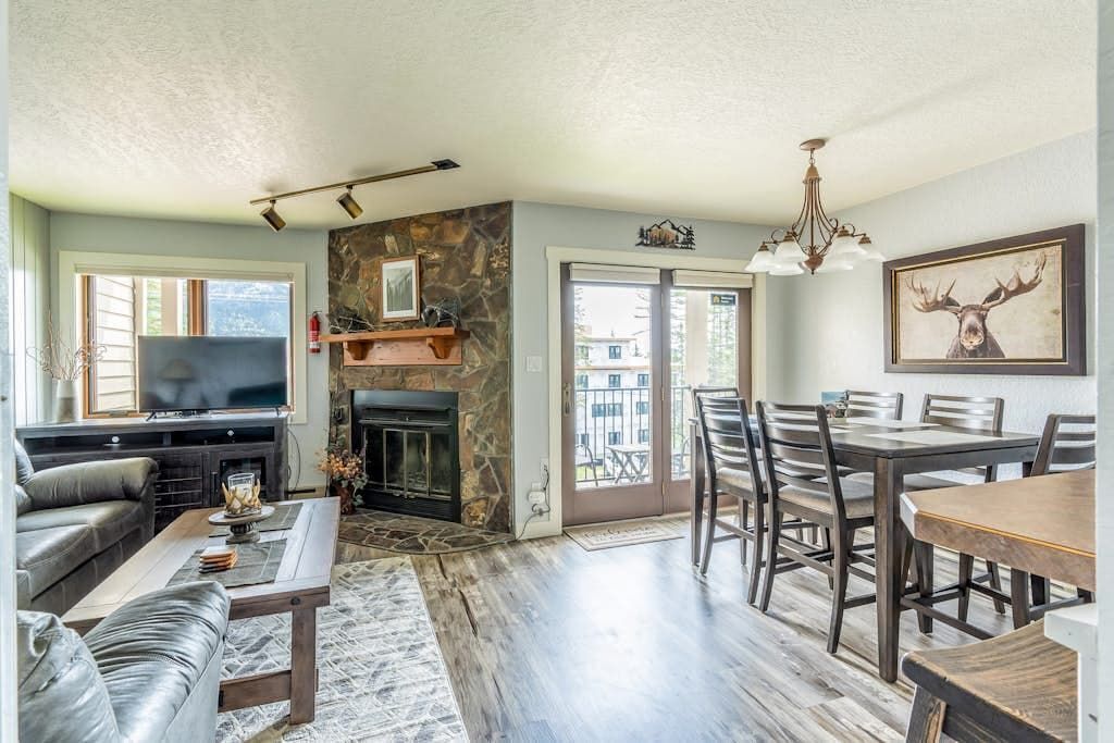 A living room with a fireplace, a television, and a dining area with chairs and a table.
