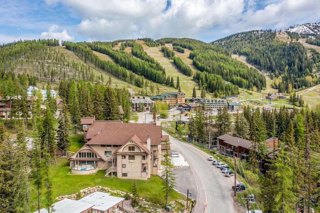 A mountainous area with a large building that appears to be a hotel, surrounded by trees and a road.