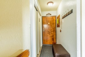 A hallway with a wooden door, a bench, and a coat rack. - Altitude Adjustment | Ski. Shred. Repeat. (Whitefish)