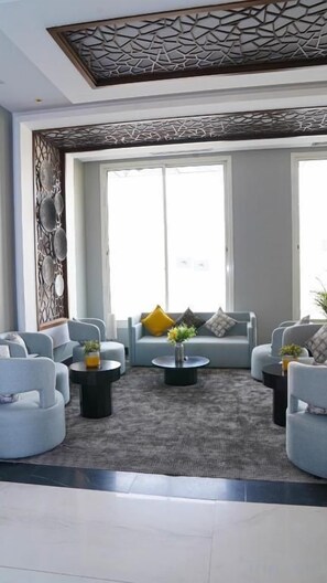 Ein modernes Wohnzimmer mit einer Sofagarnitur, runden Couchtischen und dekorativer Wandkunst.