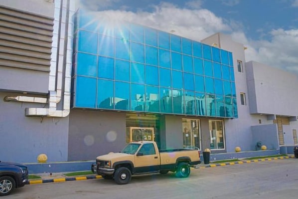 A building with a reflective glass facade, a parked pickup truck, and a clear sky. - Clowzer Al Rabea (Riyadh)