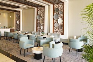 A hotel lobby with multiple seating areas, a reception desk, and decorative wall panels. - Clowzer Al Rabea (Riyadh)