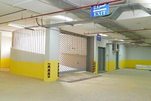 An exit sign, a metal gate, and a yellow and white wall in a parking garage. - Clowzer Al Rabea (Riyadh)