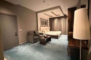 A hotel room with a bed, a chair, a desk, and a lamp. - Clowzer Al Rabea (Riyadh)