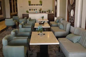 A hotel lobby with seating arrangements, a reception desk, and decorative plants. - Clowzer Al Rabea (Riyadh)