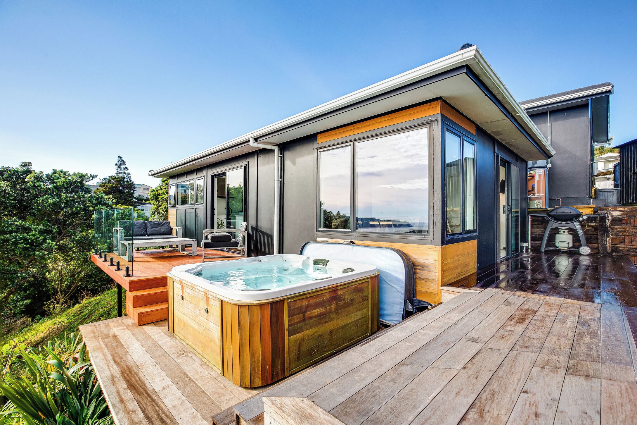 A modern house with a hot tub, outdoor seating, and a deck.