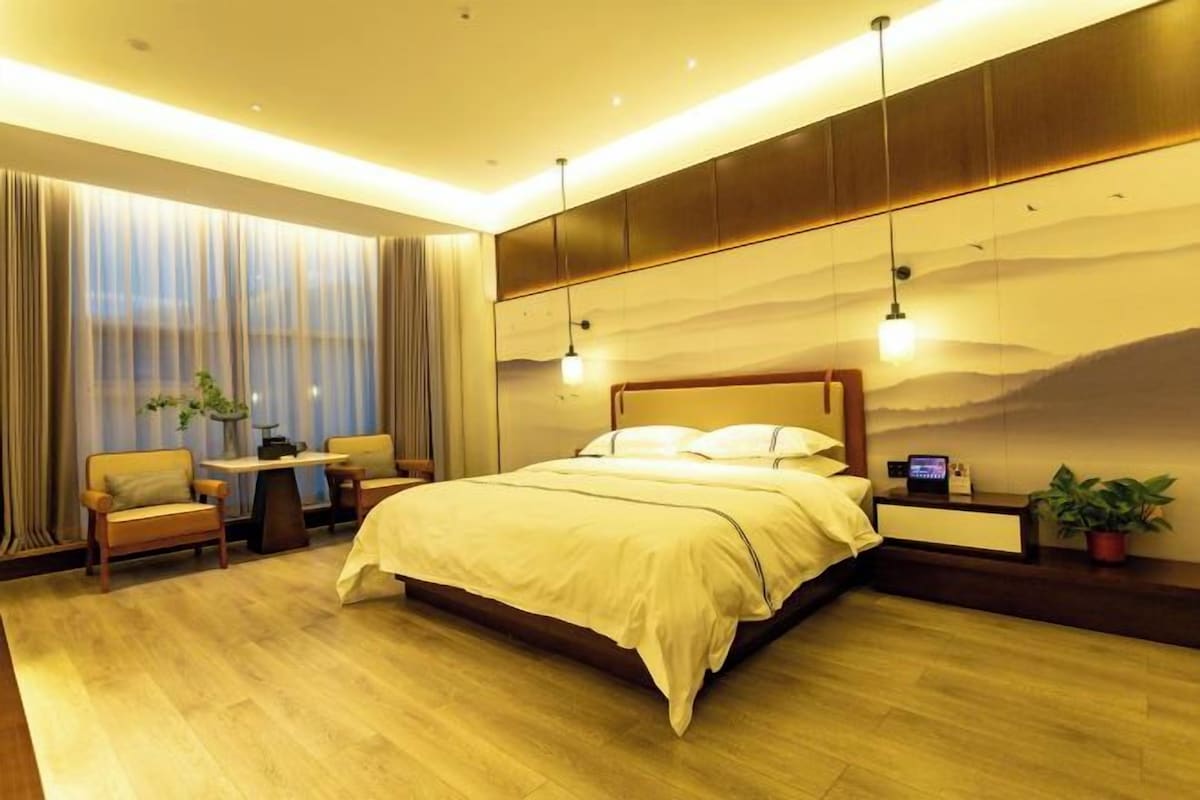 Una habitación de hotel moderna con una cama grande, un escritorio y vistas a la ciudad.