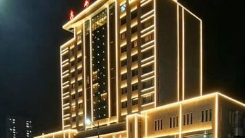A multi-story hotel with a modern facade, illuminated by internal lighting.