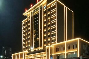 Un hotel de varios pisos con fachada moderna, iluminado por luces internas.