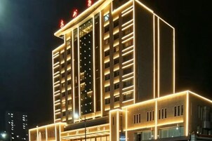 A multi-story hotel with a modern facade, illuminated by internal lighting.