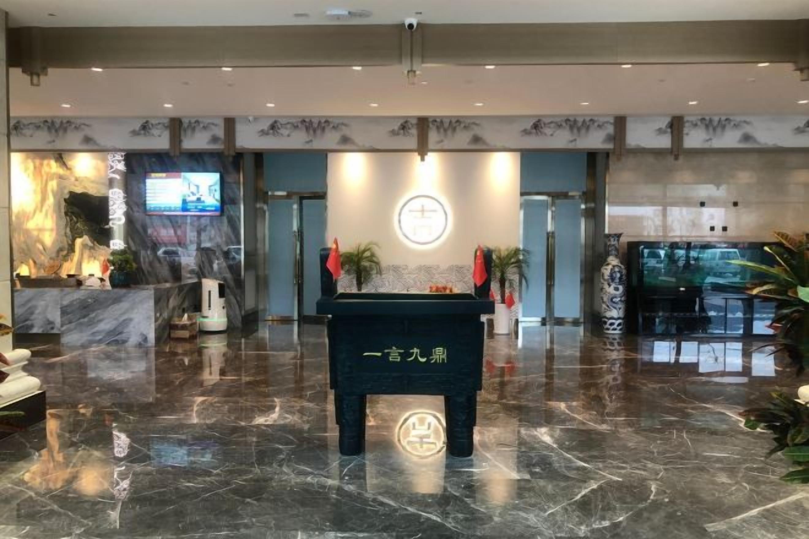 A lobby with a reception desk, a digital screen, and a decorative wall.