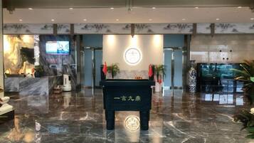 A lobby with a reception desk, a digital screen, and a decorative wall.