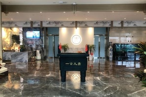 Un hall con una recepción, una pantalla digital y una pared decorativa.