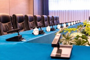 A conference room with a long table, multiple chairs, and a row of teapots.