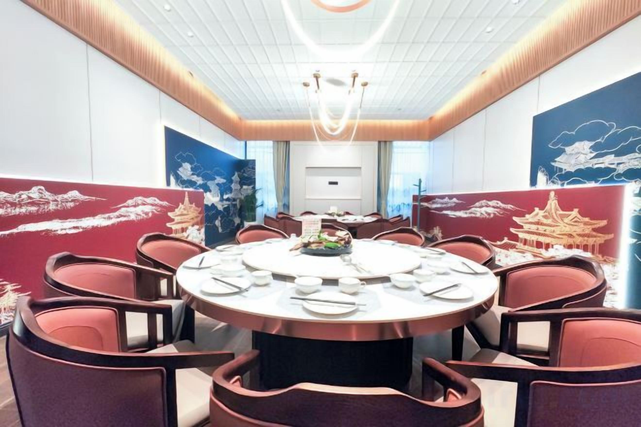A conference room with a round table, chairs, and a ceiling light fixture.