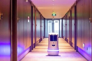 Un pasillo de hotel con un robot aspirador en el centro.