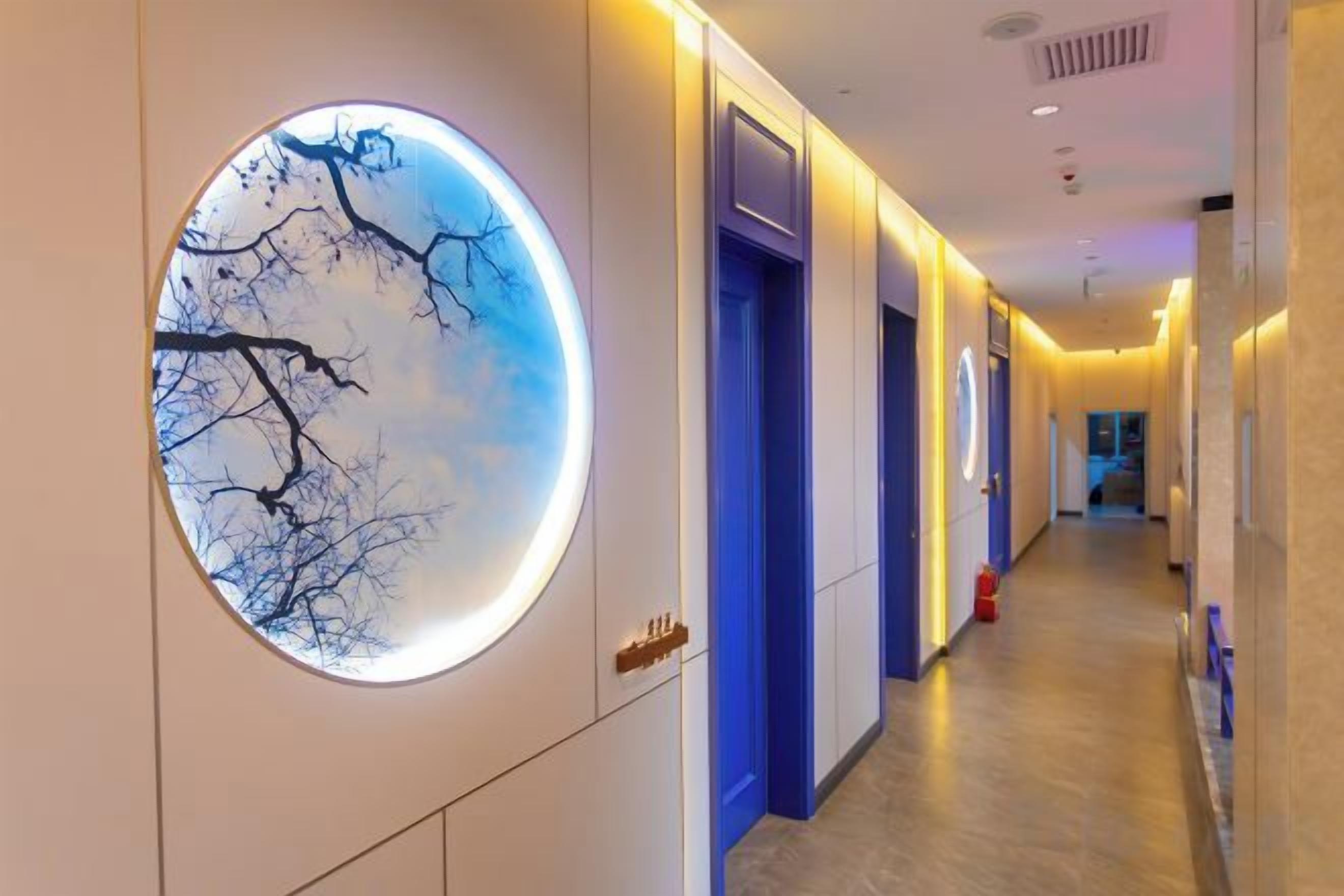 A hotel corridor with a circular wall feature, doors, and a fire extinguisher.