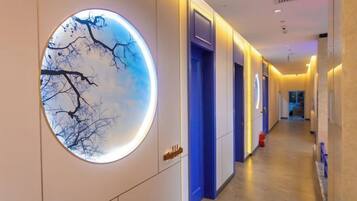 A hotel corridor with a circular wall feature, doors, and a fire extinguisher.