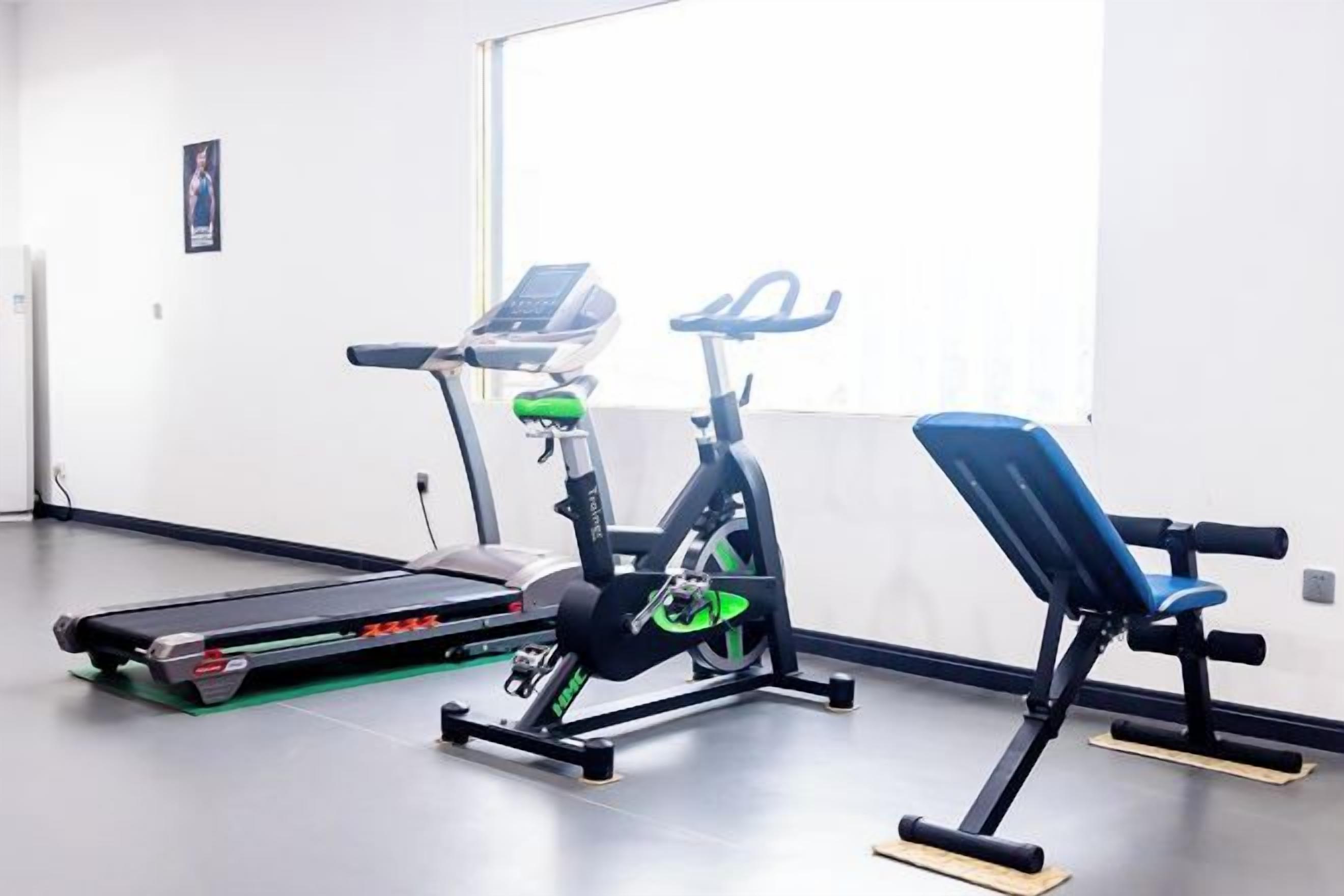 A gym with exercise equipment including a treadmill, stationary bike, and bench.