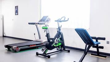 A gym with exercise equipment including a treadmill, stationary bike, and bench.