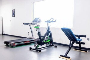 A gym with exercise equipment including a treadmill, stationary bike, and bench.
