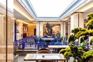 A modern indoor dining area with blue seating, a central table, and a view of the sky through a skylight.