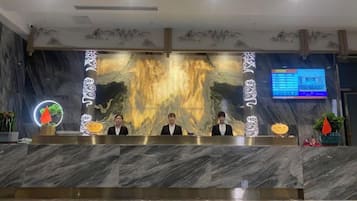 En receptionsdisk med en marmorskiva, en digital skärm och en dekorativ vägg.