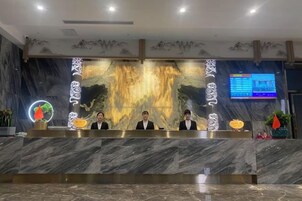 A reception desk with a marble counter, a digital screen, and a decorative wall.