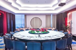 Un salón de conferencias con una mesa redonda, sillas y una decoración central.