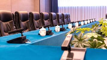 Un salón de conferencias con una larga mesa, varias sillas y una fila de teteras.