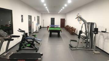 A gym with exercise equipment, a pool table, and a billiards table.