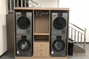 A laundry room with two stacked washing machines and a small cabinet.