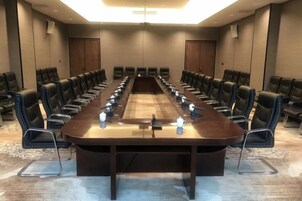 Un salón de conferencias con una larga mesa, varias sillas y piso alfombrado.