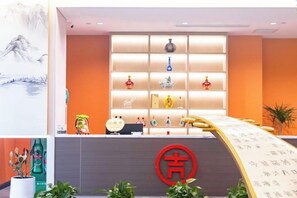 A reception area with a modern design, featuring a reception desk, a wall with shelves displaying various items, and a large red logo.