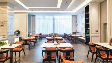 A spacious dining area with multiple tables and chairs, large windows with sheer curtains, and a modern interior design.