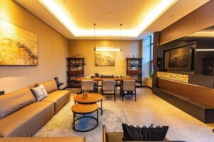 Una sala de estar moderna con un sofá, una mesa de centro, un comedor y un televisor de pantalla plana montado en la pared.