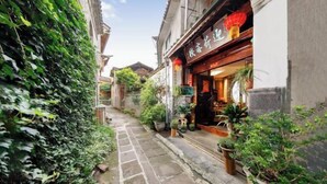 A narrow alley with buildings on either side, potted plants, and a shop with a red lantern. - Tengchong Yinghe sightseeing Inn (Tengchong)