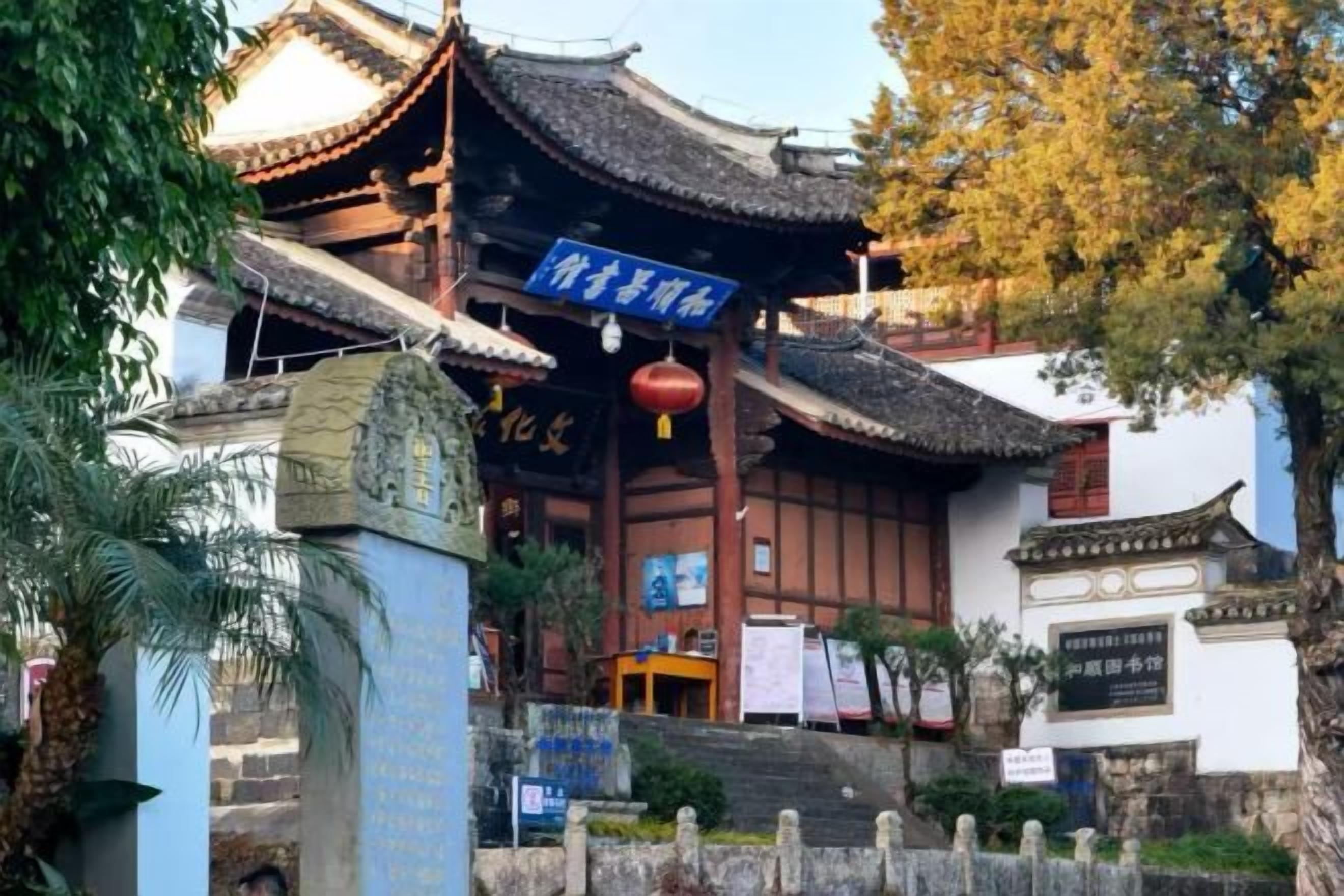 A traditional Chinese building with a tiled roof, a stone entrance, and a signboard.