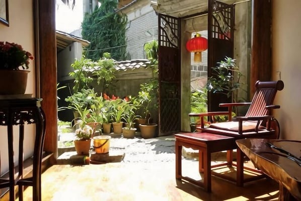 A patio with a wooden table and chairs, potted plants, and a red lantern.