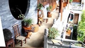 A wooden staircase leading to a balcony with a view of a cozy interior space featuring a wooden chair, a round wooden table, and various potted plants. - Tengchong Yinghe sightseeing Inn (Tengchong)