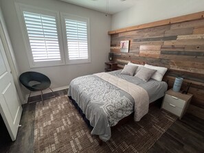 A bedroom with a bed, a nightstand, a chair, and a wooden headboard. - Charming 2-bedroom townhome in Imperial Beach, close to Coronado (Imperial Beach)