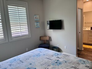 A bedroom with a bed, a television on the wall, a window with blinds, and a door leading to a bathroom. - Charming 2-bedroom townhome in Imperial Beach, close to Coronado (Imperial Beach)