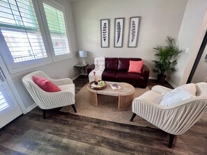 A living room with a dark red sofa, two white armchairs, a coffee table, and a potted plant. - Charming 2-bedroom townhome in Imperial Beach, close to Coronado (Imperial Beach)