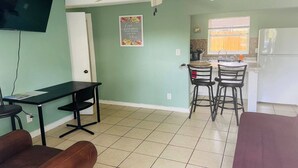 A room with a dining table, chairs, a television, and a kitchen area with a refrigerator. - Downtown Sarasota 2BR Apartment 2BA Pet Friendly Beaches Sleeps 5 (Sarasota)