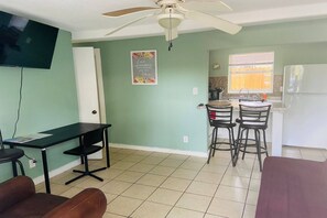 A room with a dining table, chairs, a television, and a kitchen area with a refrigerator. - Downtown Sarasota 2BR Apartment 2BA Pet Friendly Beaches Sleeps 5 (Sarasota)