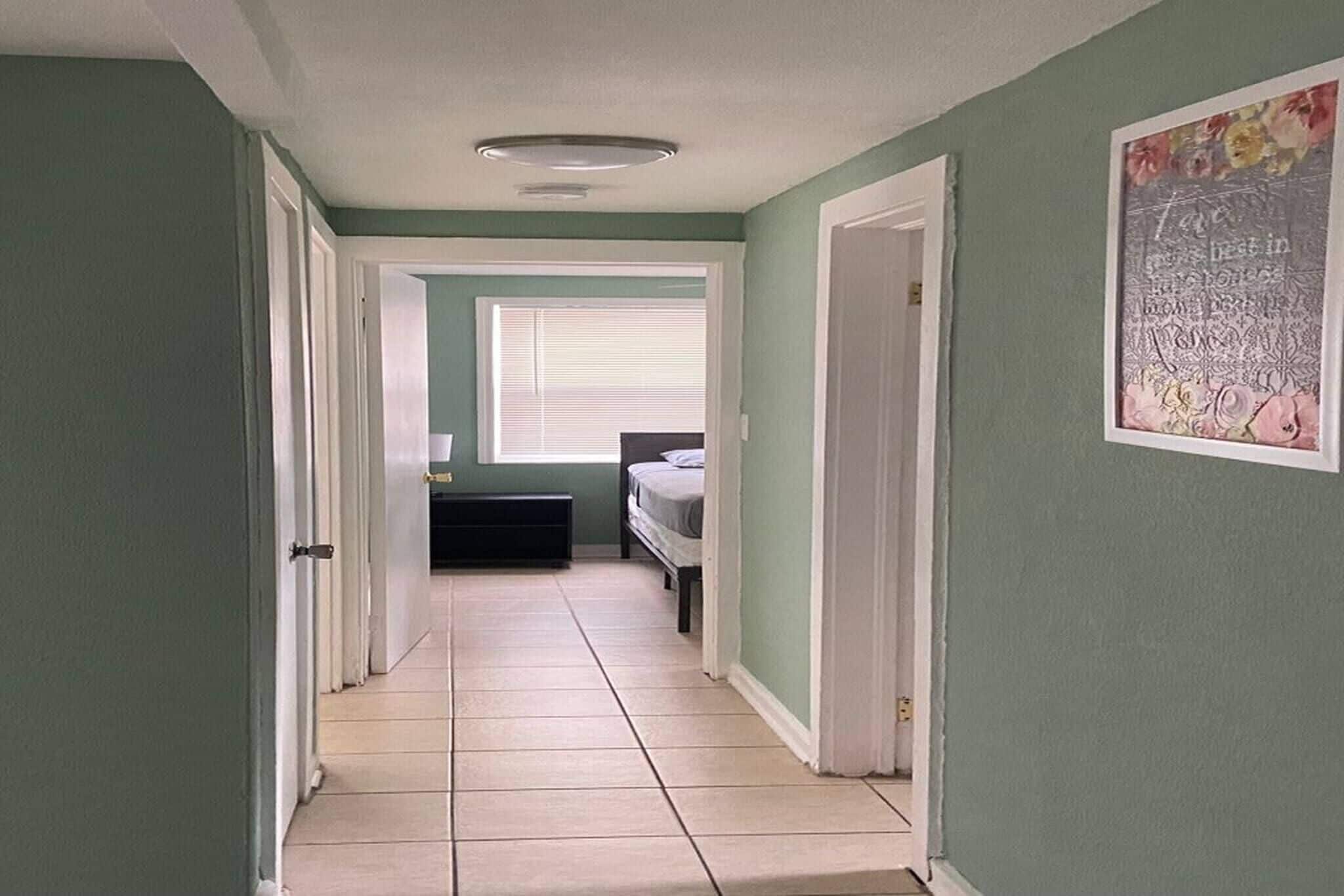 Un couloir menant à une chambre à coucher, qui contient un lit et une fenêtre.