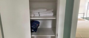 A hotel room with a bed, a shelf with folded towels, and a red cooler. - Downtown Sarasota 2BR Apartment 2BA Pet Friendly Beaches Sleeps 5 (Sarasota)