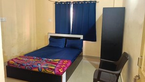A room with a bed, a chair, a curtain, and an air conditioning unit. - Hotel Bindusagar (Bhubaneswar)