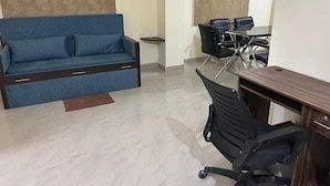 A room with a sofa, a desk with a chair, and a patterned wall. - Hotel Bindusagar (Bhubaneshwar)
